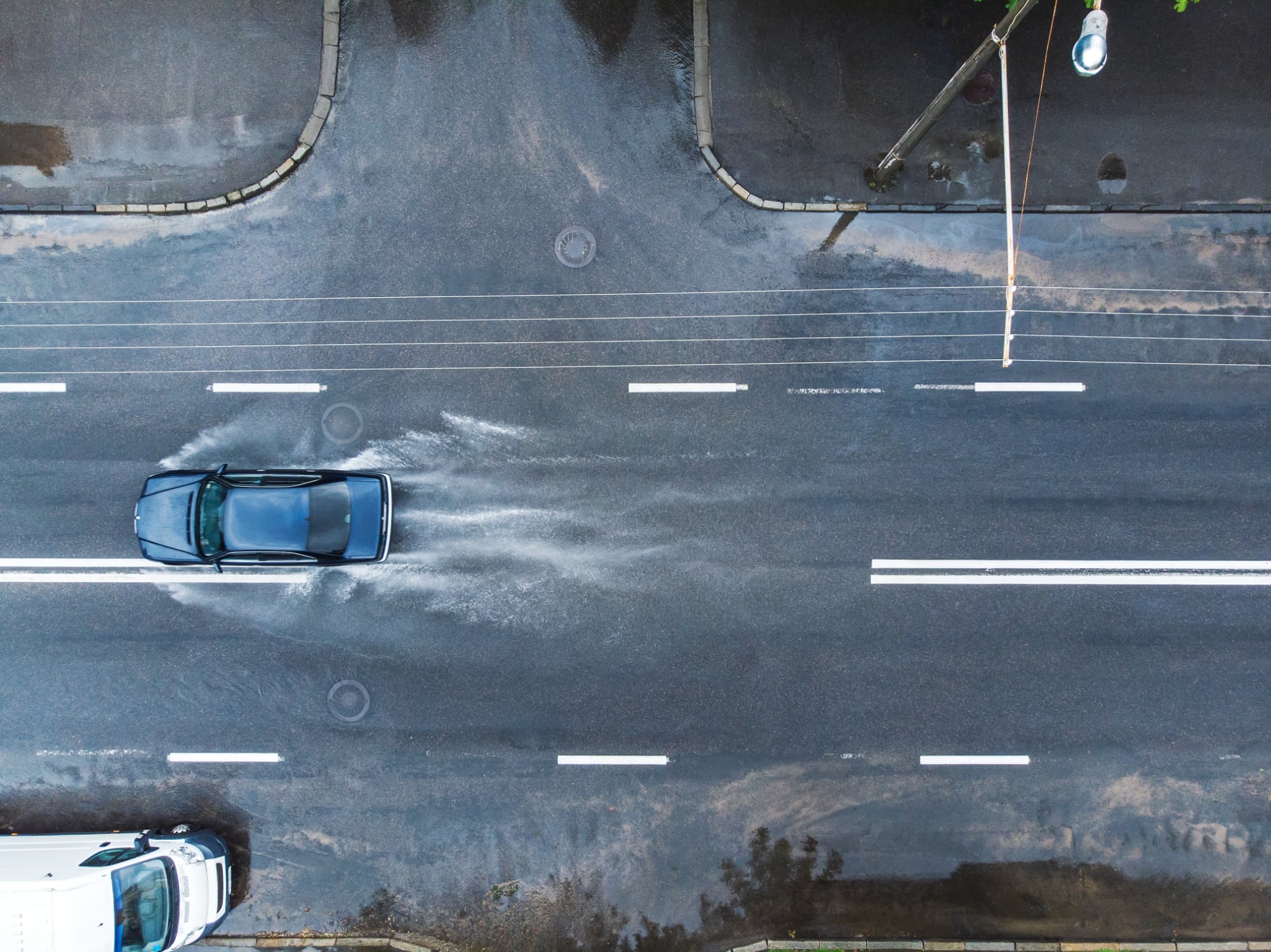 Aerial photo of car driving on rain soaked street